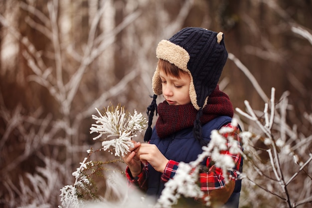 Portret uroczego chłopca w śnieżnym lesie w zimie
