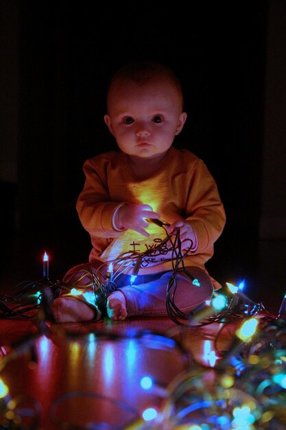 Zdjęcie portret uroczego chłopca z oświetlonymi światłami na drewnianej podłodze