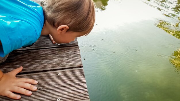 Portret Uroczego Małego Chłopca Patrzącego Na Taflę Jeziora I Obserwującego Mnóstwo Pływających Na Wodzie Nartostrad