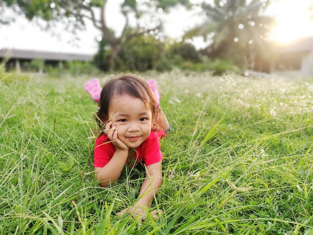 Portret uroczej dziewczynki leżącej na trawiastym polu