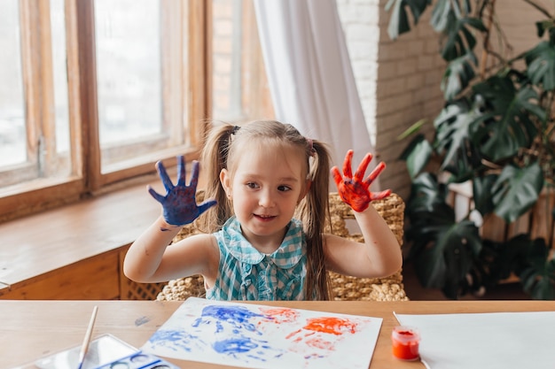 Portret Uroczej Dziewczynki Rysuje Farbami I Rękami Malowane Dłonie Dla Dzieci