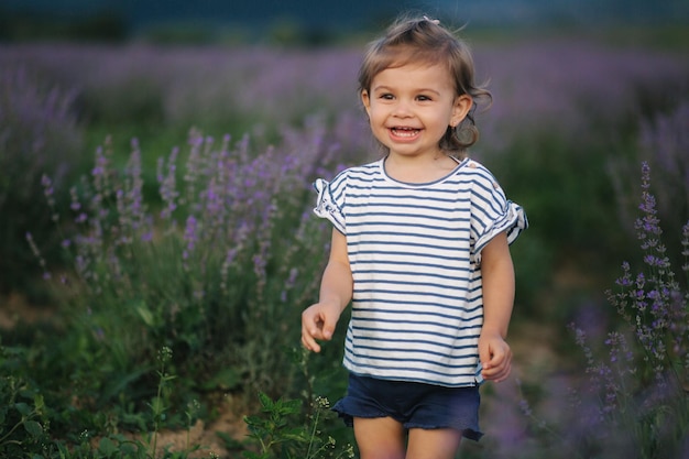 Portret uroczej dziewczynki spaceru w polu lawendy po zachodzie słońca Lawenda niebieska lub purpurowa Szczęśliwy uśmiech dzieciaka biegać i skakać