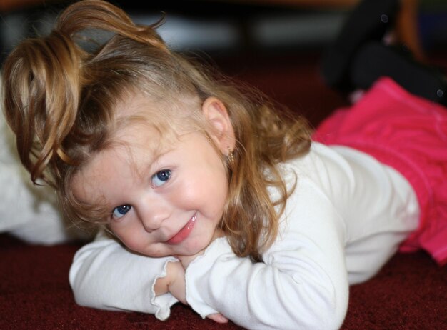 Zdjęcie portret uroczej dziewczyny leżącej na dywanie