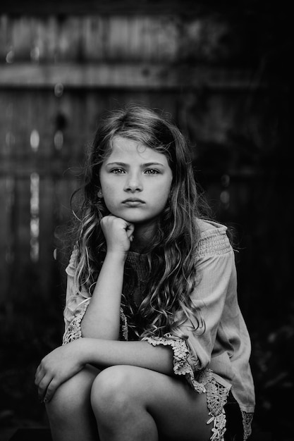 Portret uroczej dziewczyny z ręką na podbródku siedzącej w domu