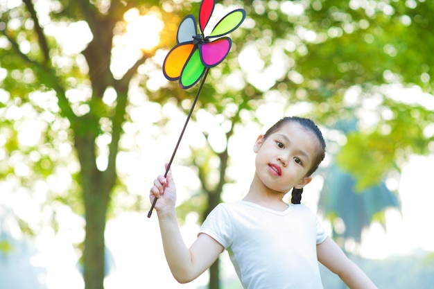 Portret uroczej dziewczyny z zabawką pinwheel stojącą na drzewach