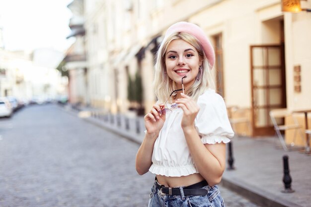 Portret uroczej młodej kobiety w beretce i okularach na europejskiej ulicy