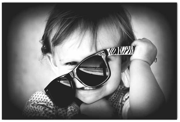 Zdjęcie portret uroczej szczęśliwej dziewczyny bawiącej się okularami przeciwsłonecznymi w domu