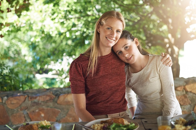 Zdjęcie portret uścisk i obiad z matką córką i szczęście ze zdrowym jedzeniem i spotkaniem towarzyskim uścisk twarzy i rodzina z rodzicem i mama z dziewczyną i dzieckiem z posiłkiem i uśmiech z słońcem