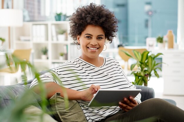 Portret uśmiech i tablet z projektantem kobieta w biurze domowym dla kreatywnego zarządzania projektami Biznes zdalna praca lub technologia do projektowania stron internetowych z pewnym siebie pracownikiem na kanapie w mieszkaniu