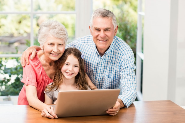 Portret uśmiechnięci dziadkowie i wnuczka używa laptop w domu