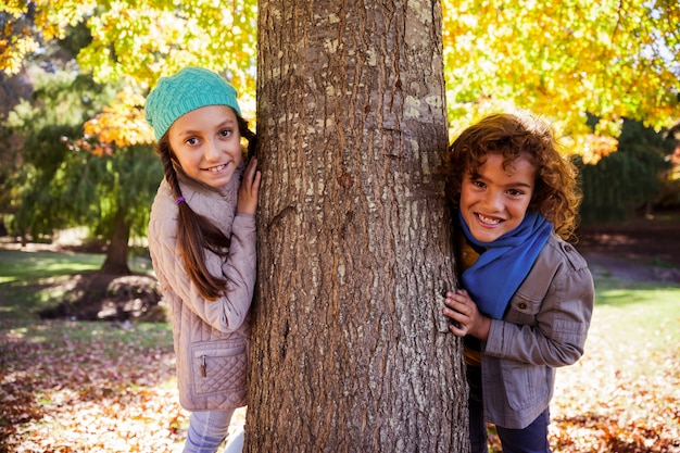 Portret uśmiechnięci rodzeństwa opiera na drzewnym bagażniku przy parkiem