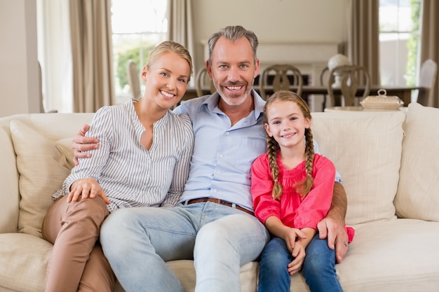 Portret uśmiechnięci rodzice i córki obsiadanie na kanapie w żywym pokoju
