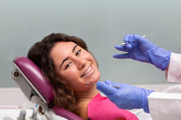 Portret uśmiechnięta dziewczyna patrząc na kamery, siedząc w fotelu kliniki dentystycznej.