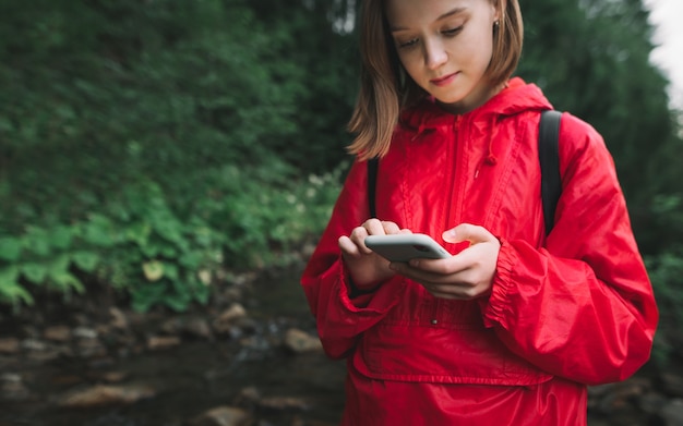 Portret Uśmiechnięta Dziewczyna Turysta W Lesie Ze Smartfonem W Ręku