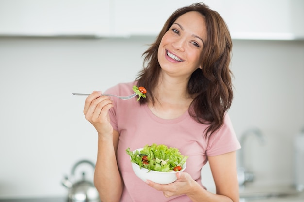 Portret uśmiechnięta kobieta z pucharem sałatka w kuchni