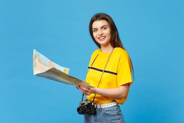 Portret uśmiechnięta młoda kobieta w żywych dorywczo ubraniach z retro vintage aparat fotograficzny trzymając papierową mapę miasta na białym tle na niebieskim tle ściany w studio. Koncepcja życia ludzi. Makieta miejsca na kopię.