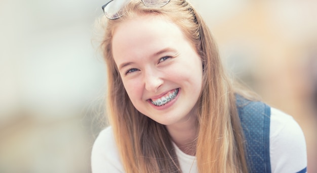 Portret uśmiechnięta piękna nastolatka z aparatami ortodontycznymi.