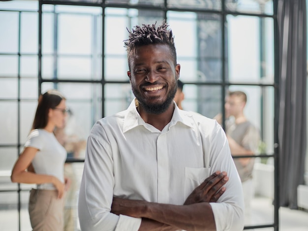 Portret uśmiechniętego Afroamerykańskiego biznesmena z kierownictwem pracującym w tle