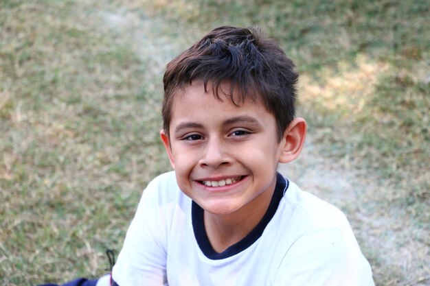 Zdjęcie portret uśmiechniętego chłopca siedzącego na lądzie