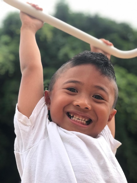 Zdjęcie portret uśmiechniętego chłopca wiszącego na pręcie