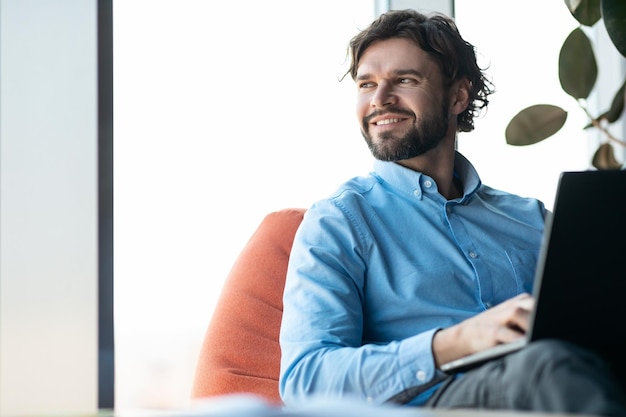 Portret uśmiechniętego dojrzałego biznesmena korzystającego z laptopa do projektu online w nowoczesnej kopii biurowej firmy