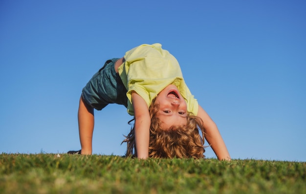 Portret uśmiechniętego dziecka do góry nogami na zielonej trawie ładny chłopiec dzieciak cieszący się przyrodą na zewnątrz zdrowy