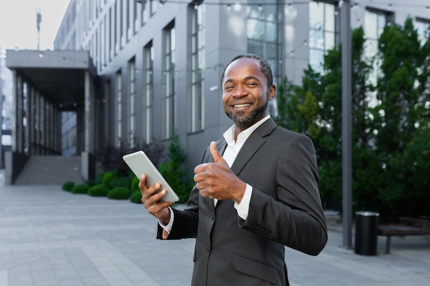 Portret uśmiechniętego i odnoszącego sukcesy czarnego starszego biznesmena stojącego w pobliżu centrum biurowego i
