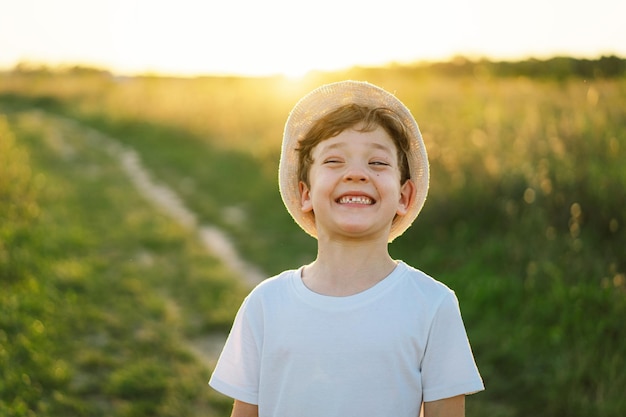 Portret uśmiechniętego małego chłopca w białej koszulce podnoszącego ręce i bawiącego się