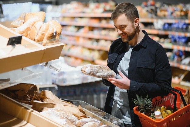 Portret uśmiechniętego mężczyzny chodzącego z wózkiem w przejściu w supermarkecie