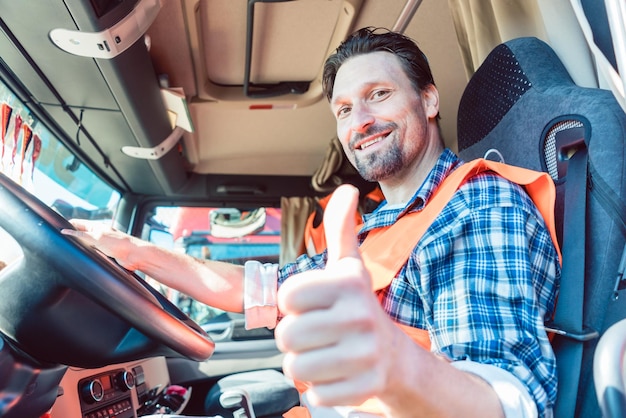 Zdjęcie portret uśmiechniętego mężczyzny gestującego siedzącego w ciężarówce