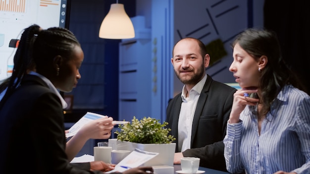 Portret uśmiechniętego mężczyzny kierownika patrzącego w kamerę pracującego w strategii firmy w sali konferencyjnej późno w nocy