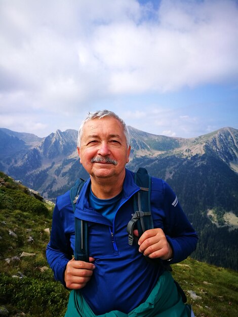 Zdjęcie portret uśmiechniętego mężczyzny stojącego na górze na tle nieba