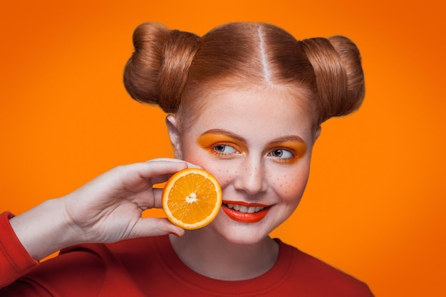 Portret uśmiechniętego mężczyzny trzymającego drinka na pomarańczowym tle