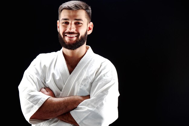 Portret uśmiechniętego mężczyzny w kimonie karate na czarnym tle