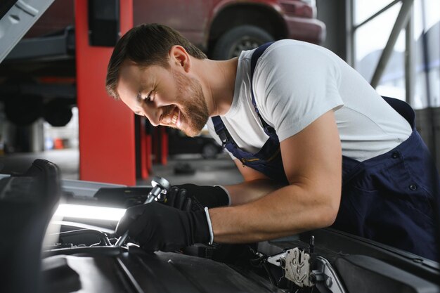 Zdjęcie portret uśmiechniętego naprawiania silnika samochodu w swoim garażu