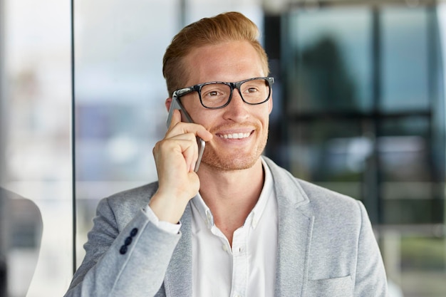 Portret Uśmiechniętego Rudowłosego Biznesmena Na Telefonie Komórkowym