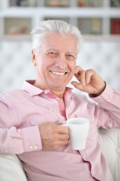 Portret uśmiechniętego starszego mężczyzny pijącego kawę