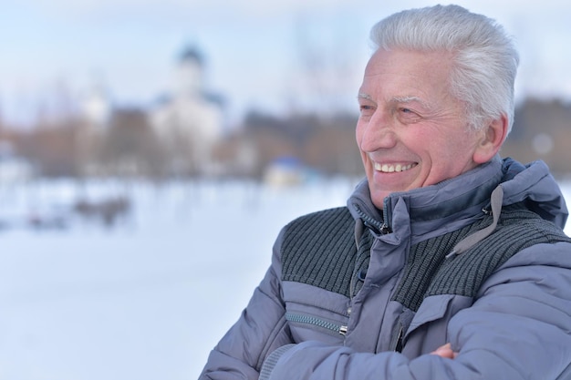 Portret uśmiechniętego starszego mężczyzny stojącego na zewnątrz w zimie