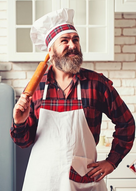 Portret uśmiechniętego szefa kuchni mężczyzny z gotowanym jedzeniem stojącego w kuchni