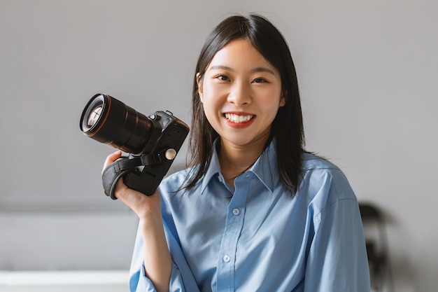 Portret uśmiechniętej azjatyckiej kobiety trzymającej aparat fotograficzny pozujący