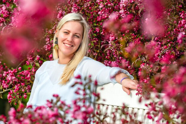 Portret uśmiechniętej blondynki w kwitnącym ogrodzie na wiosnę