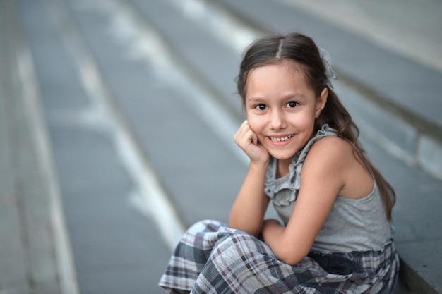 Portret uśmiechniętej dziewczynki siedzącej na schodach