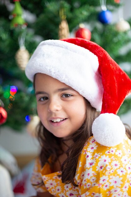 Zdjęcie portret uśmiechniętej dziewczynki w kapeluszu świętego mikołaja w czasie świąt bożego narodzenia