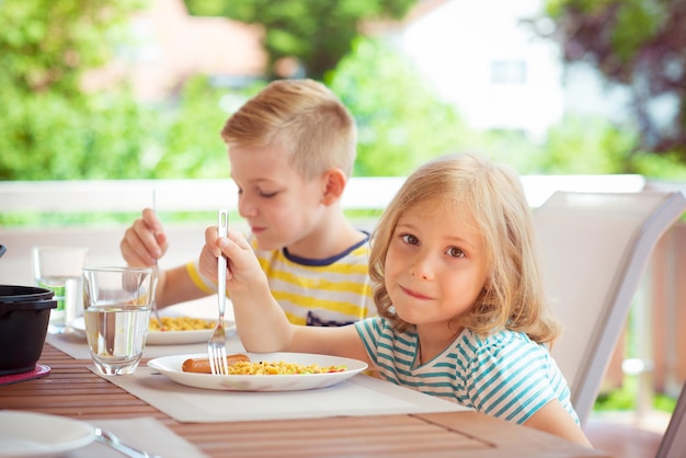 Zdjęcie portret uśmiechniętej dziewczyny jedzącej z bratem w domu