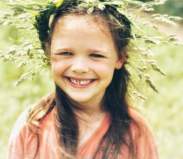 Portret uśmiechniętej dziewczyny noszącej łodygi roślin