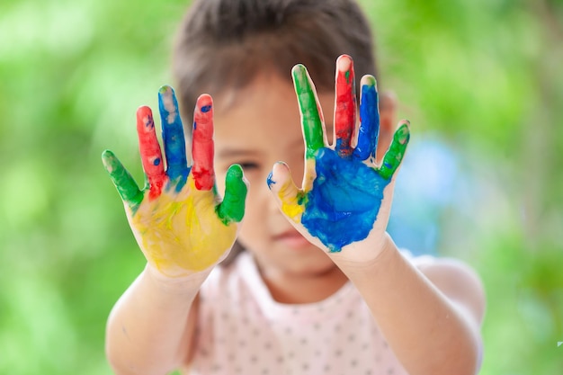 Portret uśmiechniętej dziewczyny z kolorową farbą na rękach