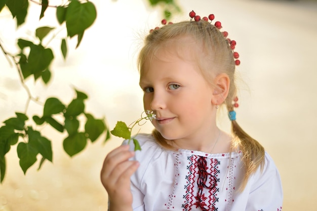 Portret uśmiechniętej dziewczyny z kwiatkiem w ukraińskiej haftowanej koszuli Dziecko dziewczynka wącha kwiat