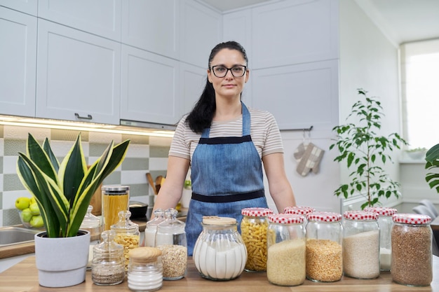 Portret uśmiechniętej kobiety gospodyni domowej w fartuchu w kuchni