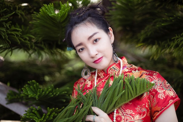 Portret uśmiechniętej kobiety w tradycyjnych ubraniach stojącej obok rośliny