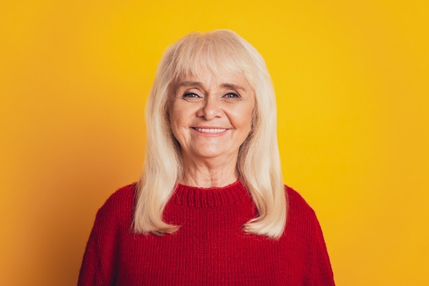 Portret uśmiechniętej kobiety w wieku na żółtym tle